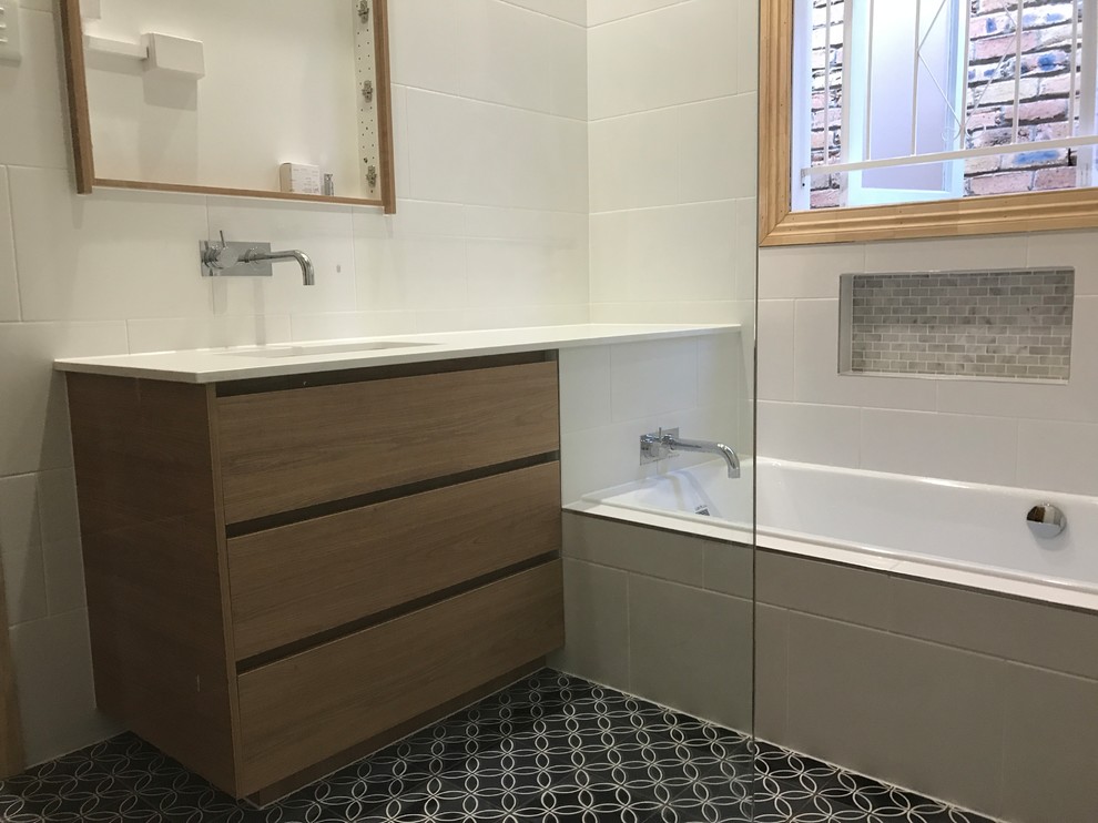 Small contemporary 3/4 bathroom in Brisbane with flat-panel cabinets, dark wood cabinets, a curbless shower, a one-piece toilet, white tile, ceramic tile, white walls, cement tiles, an integrated sink, solid surface benchtops, blue floor, a hinged shower door and white benchtops.