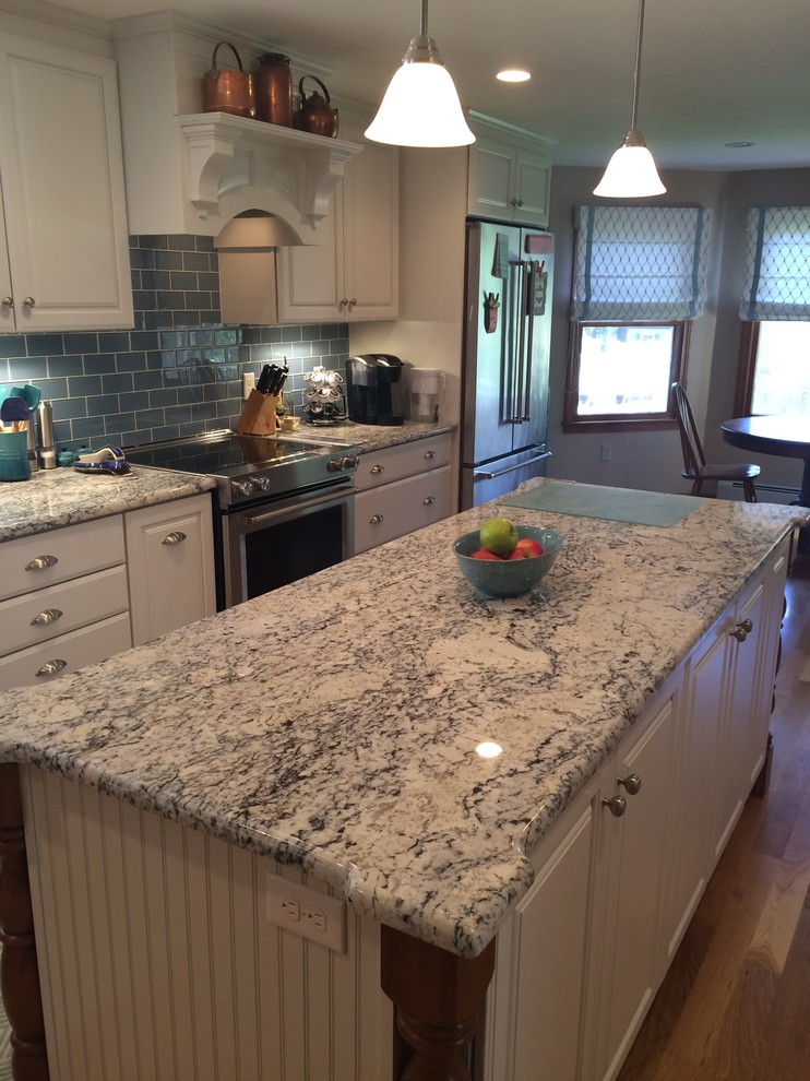 Eat-in kitchen - transitional u-shaped medium tone wood floor eat-in kitchen idea in Boston with an undermount sink, raised-panel cabinets, white cabinets, granite countertops, blue backsplash, glass tile backsplash, stainless steel appliances and an island