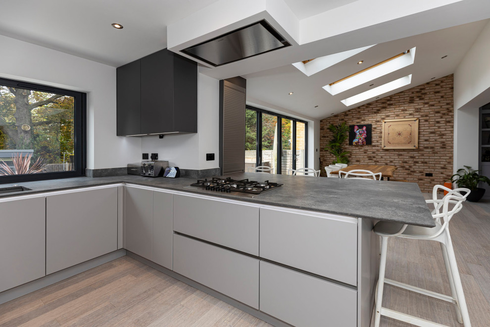 Design ideas for a mid-sized modern u-shaped kitchen in Hertfordshire with a drop-in sink, recessed-panel cabinets, concrete benchtops, grey splashback, granite splashback, stainless steel appliances, laminate floors and grey benchtop.
