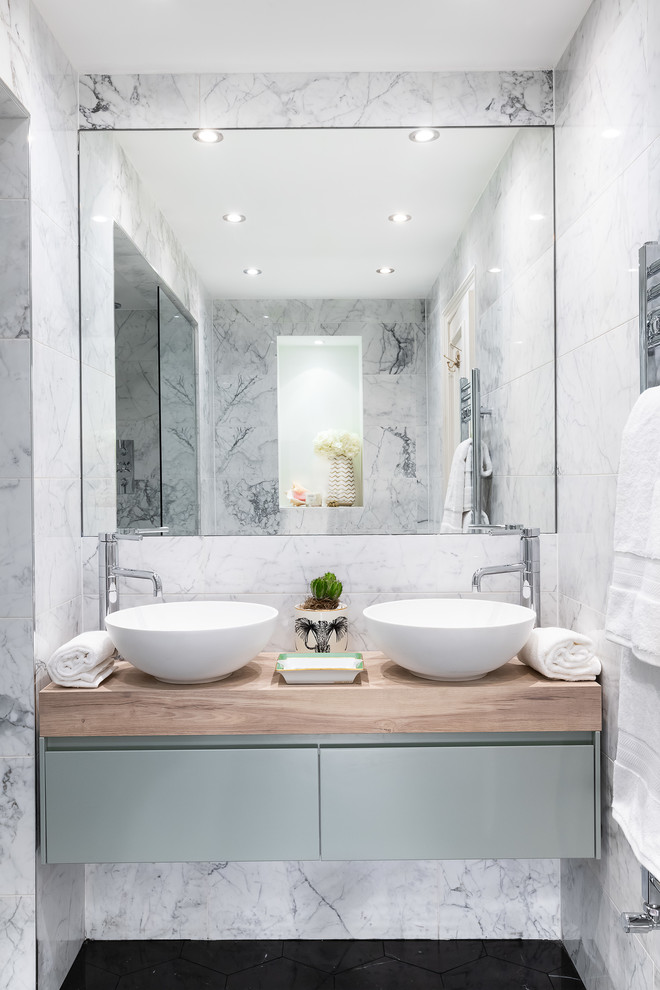 This is an example of a mid-sized contemporary master bathroom in London with flat-panel cabinets, blue cabinets, an alcove shower, gray tile, marble floors, a vessel sink, wood benchtops, black floor and brown benchtops.