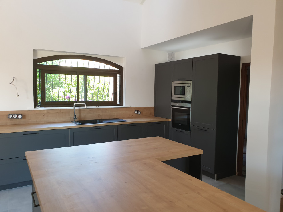 Large modern l-shaped open plan kitchen in Toulouse with with island, an undermount sink, beaded inset cabinets, stainless steel cabinets, wood benchtops, brown splashback, timber splashback, coloured appliances, ceramic floors, grey floor and brown benchtop.