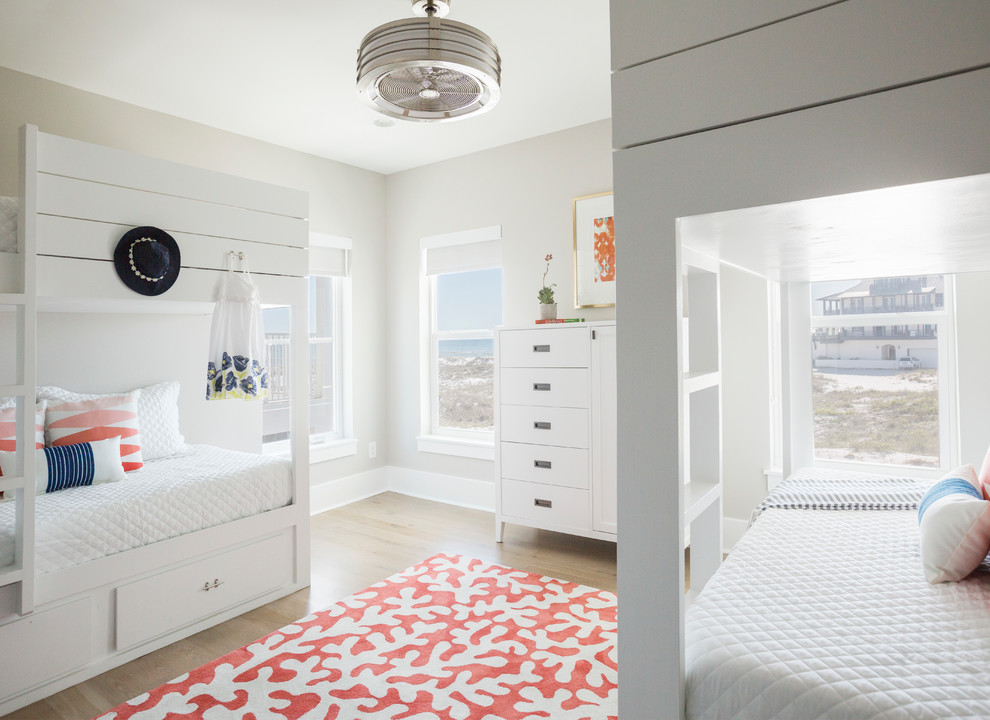 Design ideas for a beach style gender-neutral kids' bedroom for kids 4-10 years old in Miami with beige walls, light hardwood floors and beige floor.