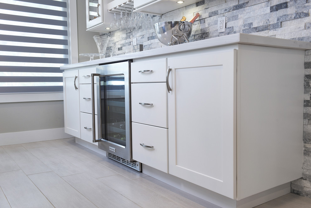 Example of a large transitional l-shaped porcelain tile and gray floor open concept kitchen design in Miami with a farmhouse sink, shaker cabinets, gray cabinets, quartz countertops, gray backsplash, marble backsplash, stainless steel appliances and two islands
