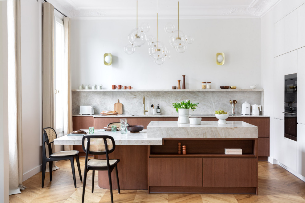 Zweizeilige Moderne Küche mit flächenbündigen Schrankfronten, hellbraunen Holzschränken, Küchenrückwand in Grau, Rückwand aus Stein, braunem Holzboden, Kücheninsel, braunem Boden und grauer Arbeitsplatte in Marseille