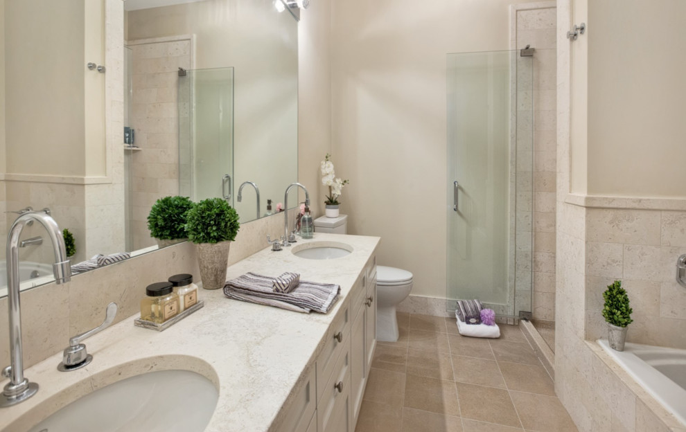 Large contemporary master bathroom in New York with shaker cabinets, white cabinets, a drop-in tub, a corner shower, a two-piece toilet, beige tile, marble, beige walls, travertine floors, an undermount sink and limestone benchtops.