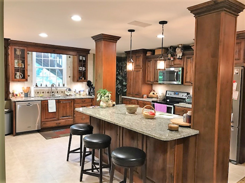 Photo of a large country l-shaped separate kitchen in Charlotte with an undermount sink, raised-panel cabinets, dark wood cabinets, granite benchtops, metallic splashback, travertine splashback, stainless steel appliances, ceramic floors, with island and beige floor.