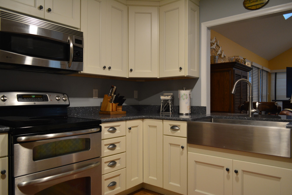 Eat-in kitchen - mid-sized transitional u-shaped dark wood floor and brown floor eat-in kitchen idea with a farmhouse sink, shaker cabinets, beige cabinets, granite countertops, gray backsplash, mosaic tile backsplash, stainless steel appliances, a peninsula and black countertops