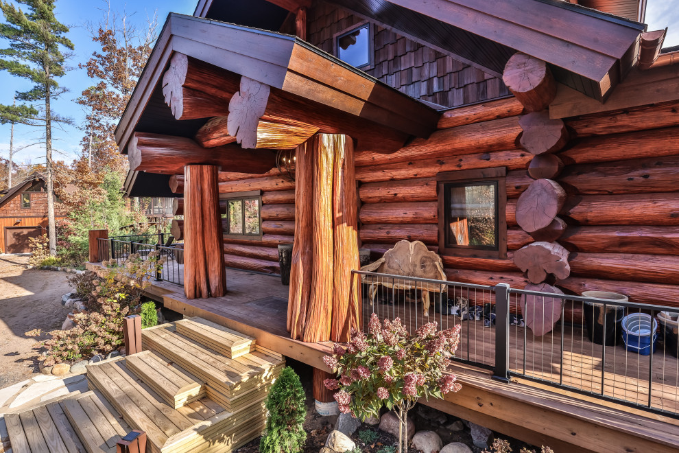 Huge mountain style ground level mixed material railing deck photo with a roof extension