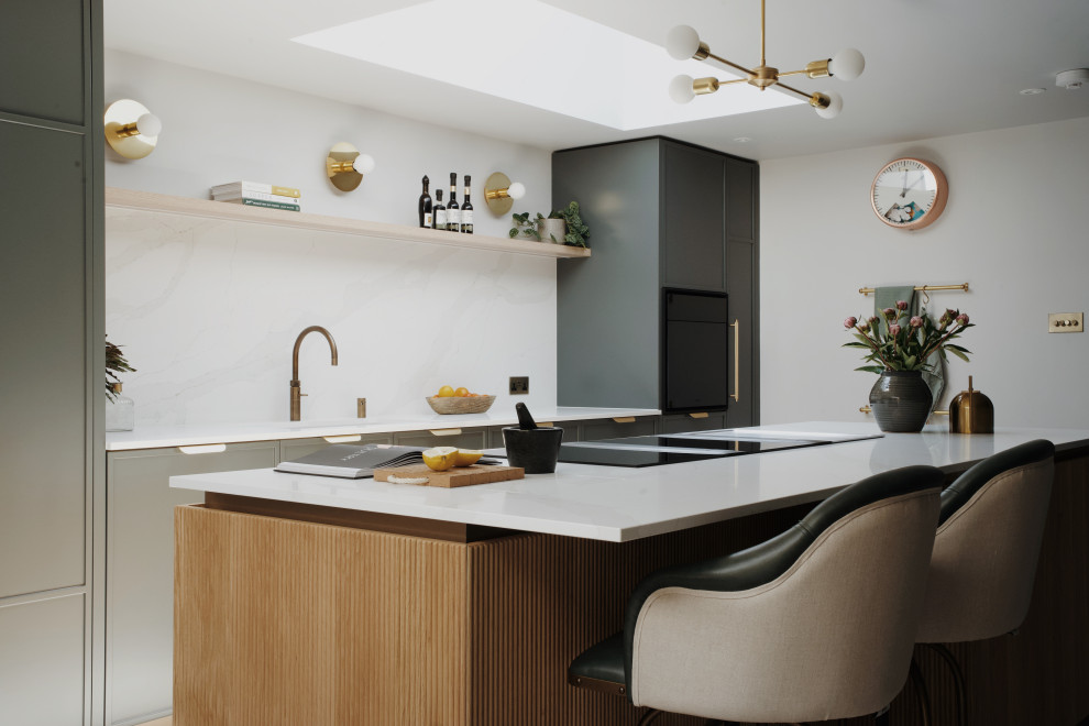 This is an example of a large contemporary single-wall kitchen/diner in London with shaker cabinets, green cabinets, quartz worktops, black appliances, an island and white worktops.