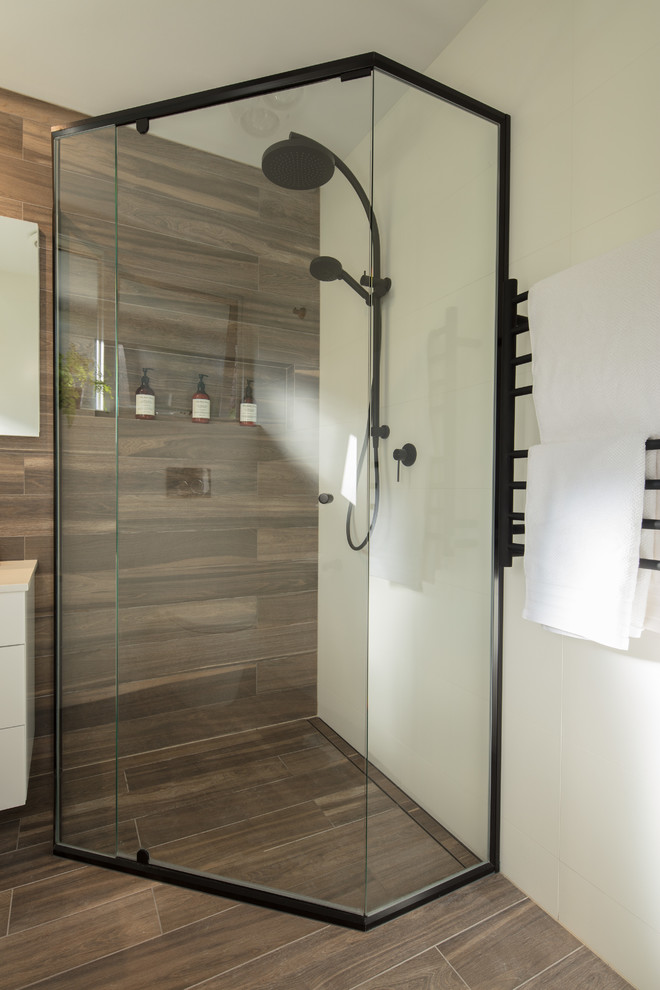 Photo of a small contemporary bathroom in Sydney with shaker cabinets, white cabinets, a corner shower, a one-piece toilet, white tile, porcelain tile, white walls, porcelain floors, a vessel sink, engineered quartz benchtops, brown floor and a hinged shower door.