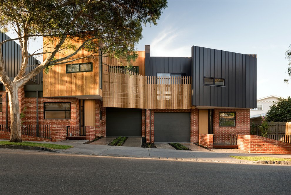Inspiration for a mid-sized contemporary two-storey black exterior in Melbourne with a flat roof and metal siding.
