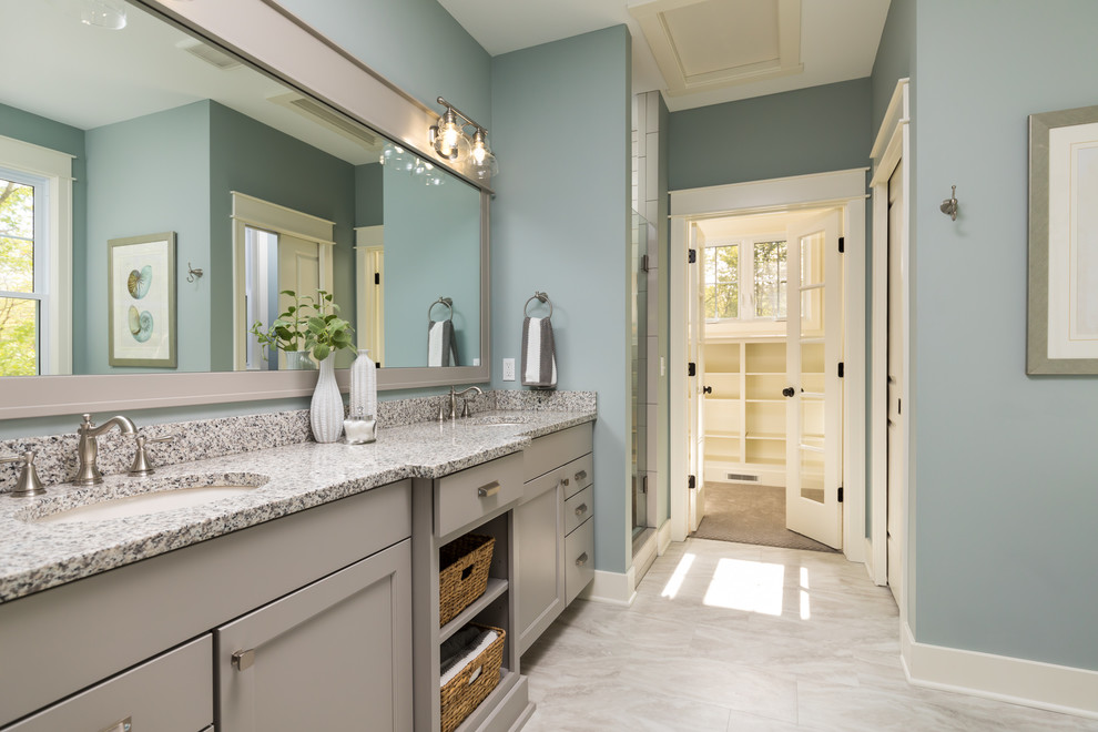 Large beach style master bathroom in Grand Rapids with flat-panel cabinets, grey cabinets, a freestanding tub, an open shower, a one-piece toilet, blue walls, laminate floors, an undermount sink, engineered quartz benchtops, beige floor and a hinged shower door.