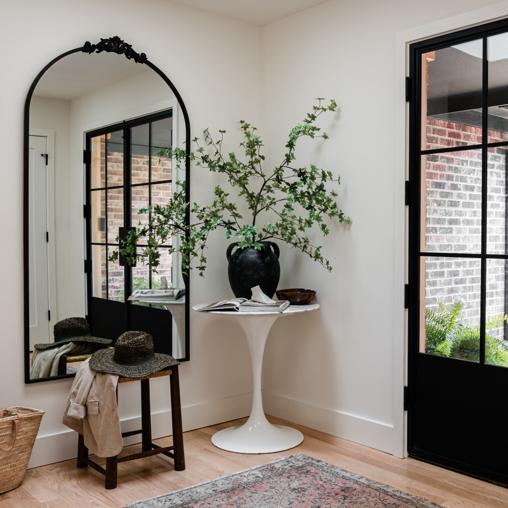 Example of a mid-sized transitional light wood floor front door design in Chicago with white walls and a black front door