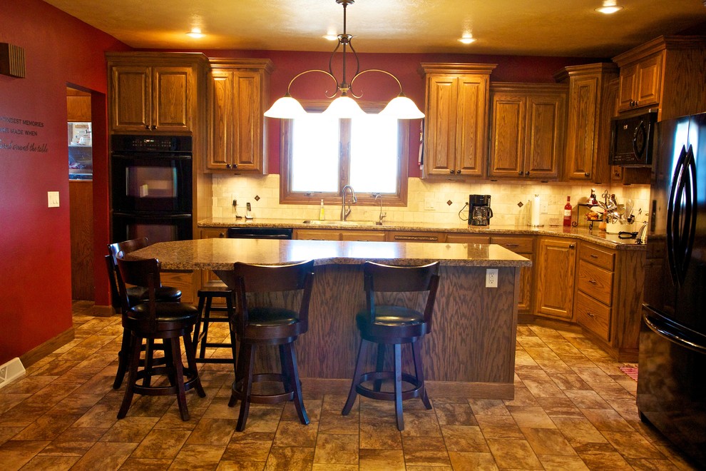 Inspiration for a mid-sized l-shaped linoleum floor open concept kitchen remodel with an undermount sink, raised-panel cabinets, medium tone wood cabinets, laminate countertops, beige backsplash, stone tile backsplash, black appliances and an island