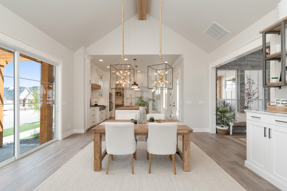 Mid-sized country kitchen/dining combo in Boise with grey walls, light hardwood floors, a standard fireplace, a stone fireplace surround and grey floor.