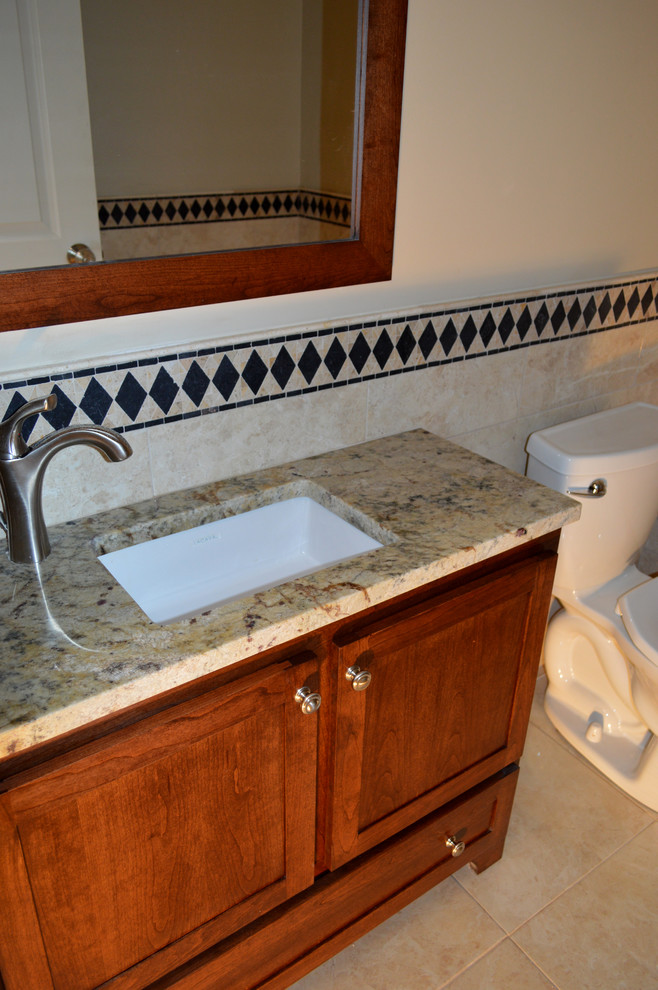 Inspiration for a transitional beige tile and ceramic tile porcelain tile home design remodel in Boston with an undermount sink, shaker cabinets, dark wood cabinets, granite countertops, a two-piece toilet and beige walls