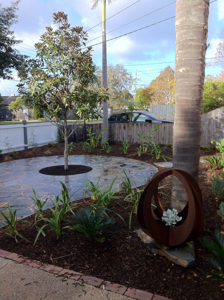 Photo of a mid-sized midcentury front yard partial sun garden in Melbourne with a garden path and natural stone pavers.