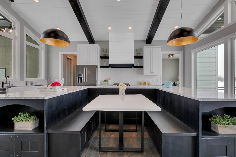 Mid-sized modern u-shaped eat-in kitchen in Minneapolis with a farmhouse sink, shaker cabinets, granite benchtops, white splashback, ceramic splashback, stainless steel appliances, medium hardwood floors, with island and grey benchtop.