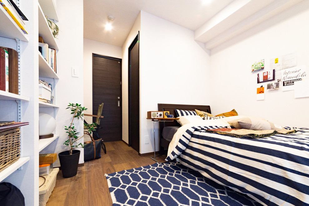 Photo of a small scandinavian bedroom in Tokyo with white walls, medium hardwood floors and brown floor.