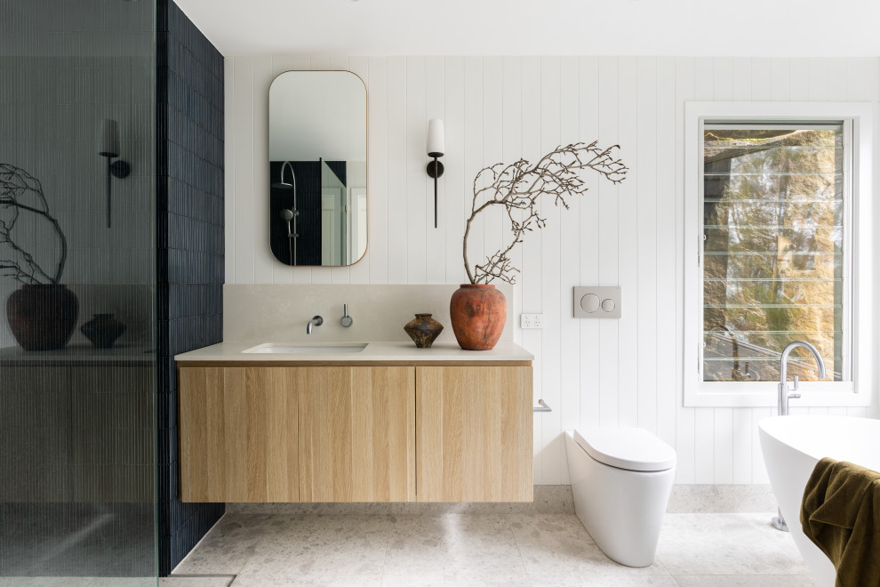 Photo of a contemporary bathroom in Sydney with flat-panel cabinets, light wood cabinets, a freestanding tub, an alcove shower, white walls, an undermount sink, grey floor, beige benchtops, a single vanity, a floating vanity and planked wall panelling.