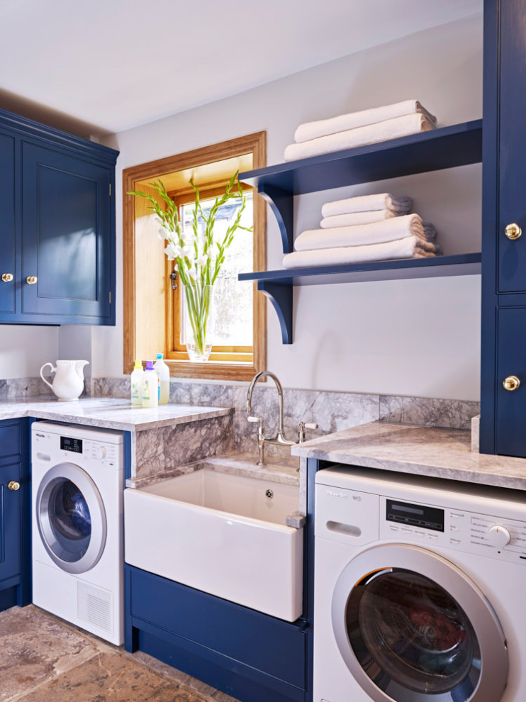 Mid-sized l-shaped dedicated laundry room in Other with a farmhouse sink, beaded inset cabinets, blue cabinets, quartzite benchtops, white walls, an integrated washer and dryer and grey benchtop.