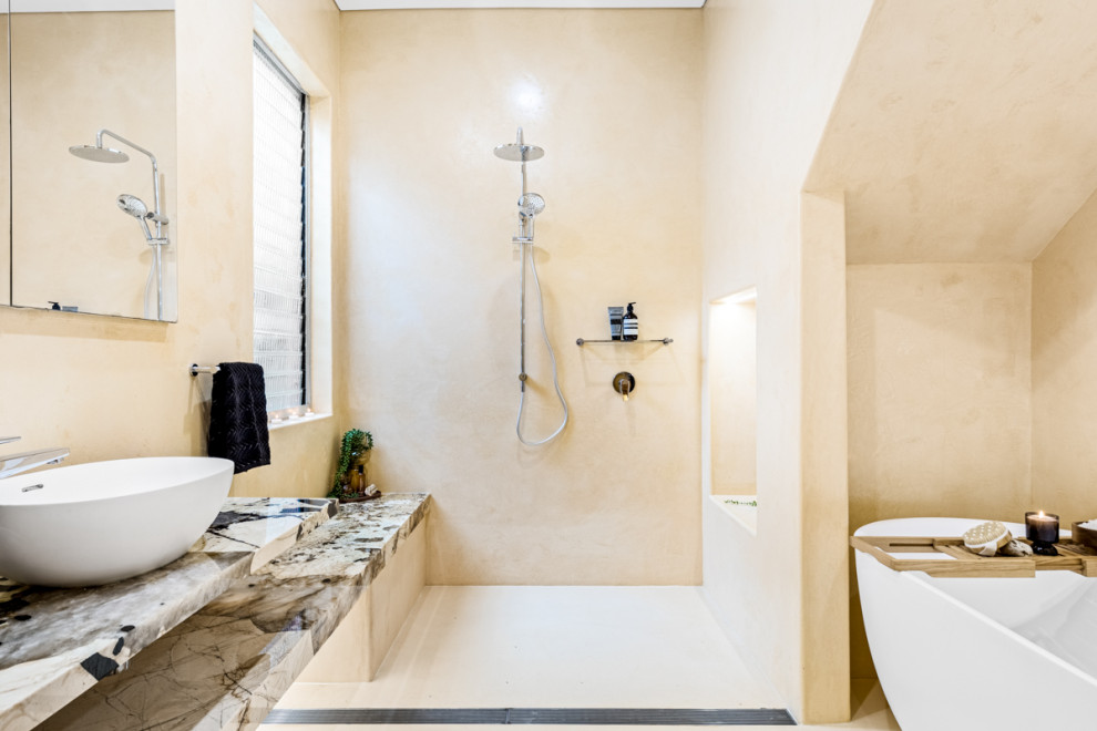 Photo of a large mediterranean master wet room bathroom in Sydney with a freestanding tub, a bidet, beige walls, concrete floors, a vessel sink, onyx benchtops, beige floor, an open shower, multi-coloured benchtops, a shower seat, a single vanity and a floating vanity.