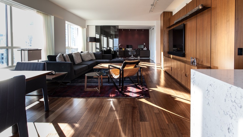 Contemporary open concept living room in Chicago with dark hardwood floors and a wall-mounted tv.
