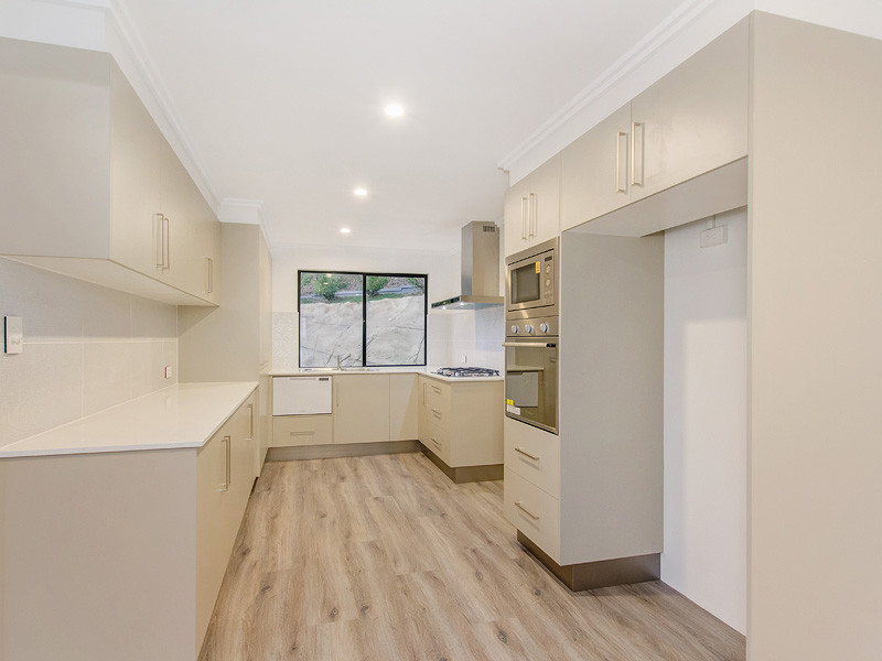 Photo of a mid-sized contemporary u-shaped open plan kitchen in Brisbane with flat-panel cabinets, beige cabinets, beige splashback, ceramic splashback, stainless steel appliances and light hardwood floors.