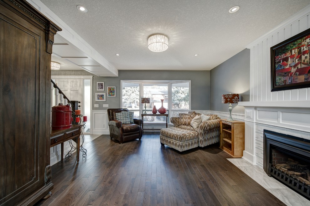 Design ideas for a mid-sized arts and crafts open concept family room in Calgary with a music area, grey walls, medium hardwood floors, a standard fireplace, a tile fireplace surround, no tv and brown floor.