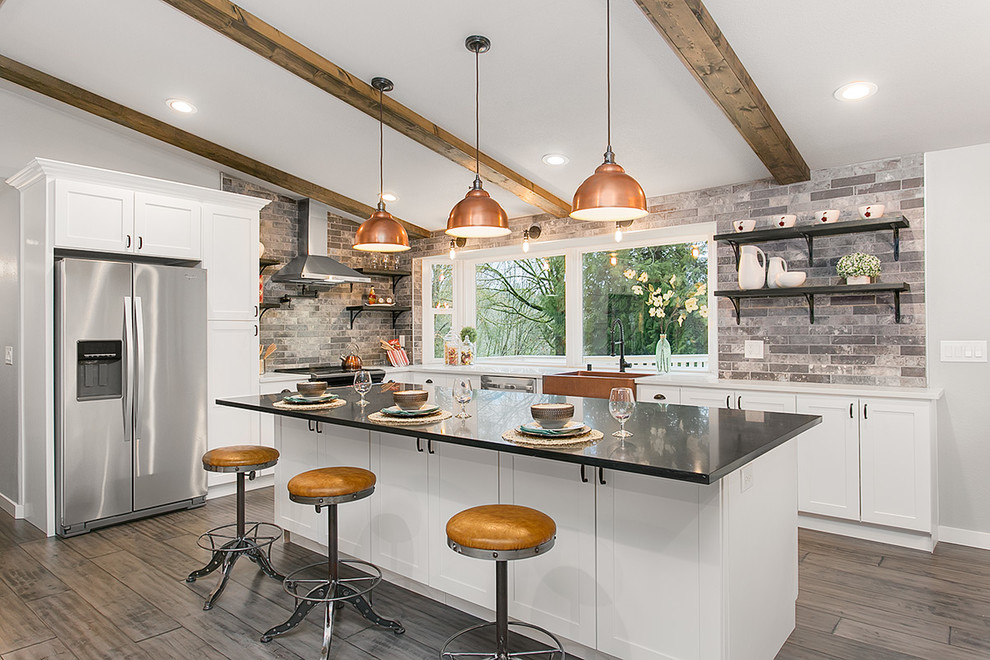 Traditional l-shaped kitchen in Seattle with a farmhouse sink, shaker cabinets, white cabinets, grey splashback, stainless steel appliances, medium hardwood floors and with island.