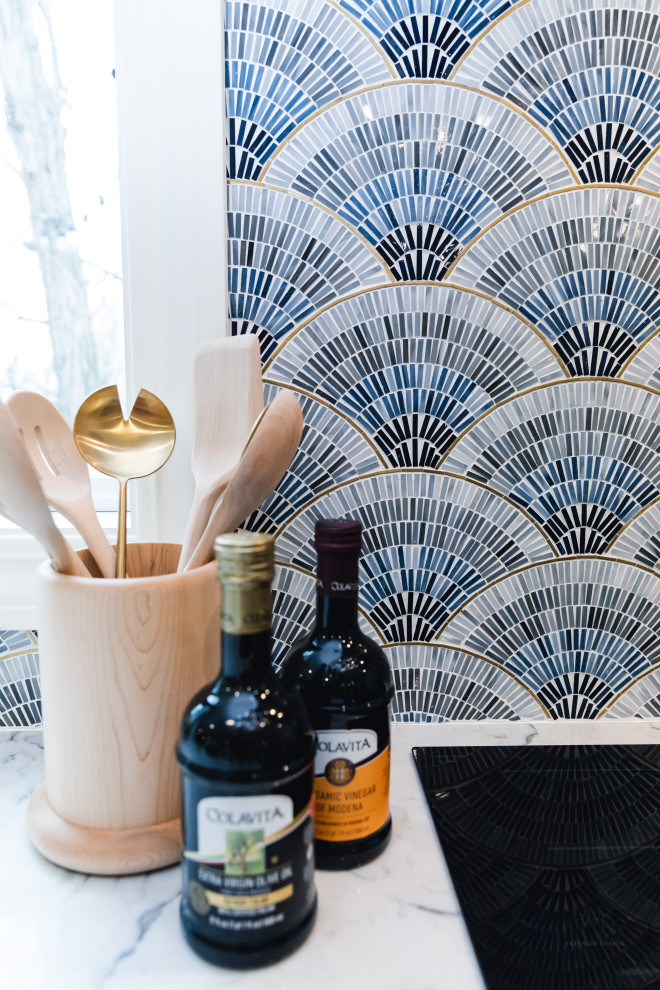 Example of a transitional light wood floor and white floor kitchen design with a farmhouse sink, flat-panel cabinets, blue cabinets, quartz countertops, blue backsplash, glass tile backsplash, stainless steel appliances, an island and white countertops