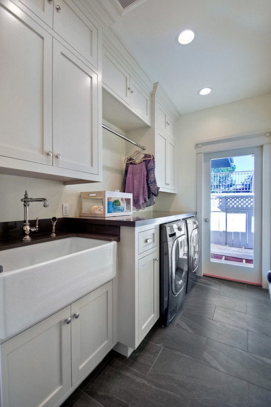Mid-sized country single-wall dedicated laundry room in San Diego with a farmhouse sink, shaker cabinets, white cabinets, white walls, slate floors and a side-by-side washer and dryer.