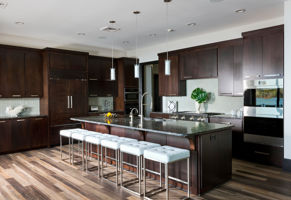 Photo of a contemporary galley kitchen in Charlotte with an undermount sink, flat-panel cabinets, dark wood cabinets, beige splashback, panelled appliances, medium hardwood floors, with island and brown floor.