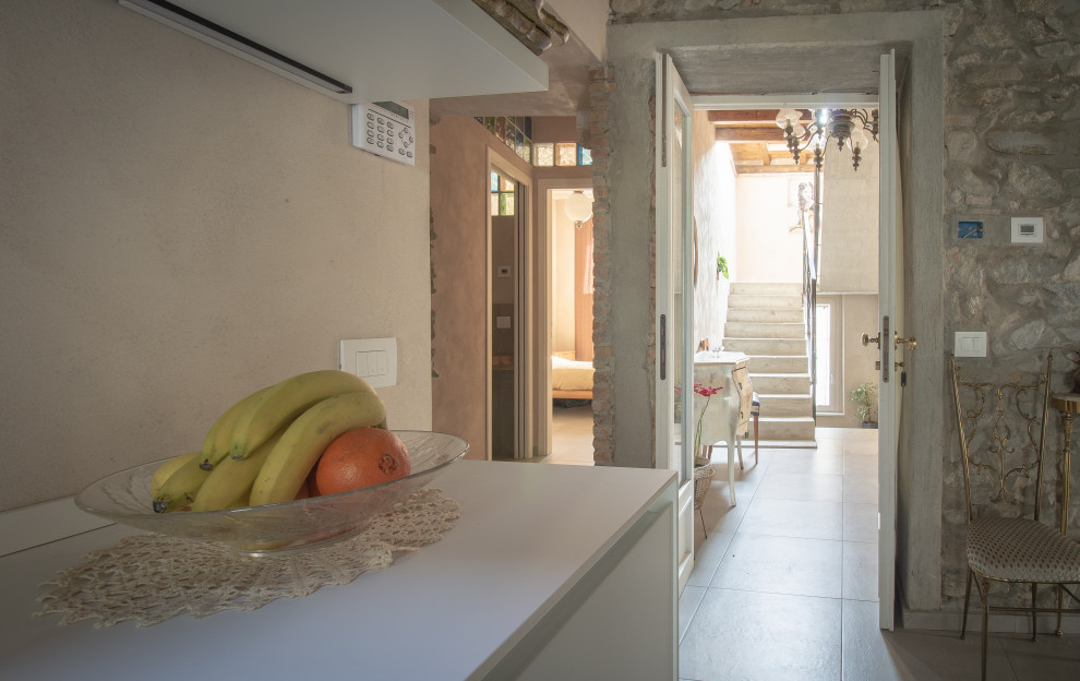 Geräumiges Stilmix Foyer mit Backsteinboden, Doppeltür, heller Holzhaustür, grauem Boden, freigelegten Dachbalken und Ziegelwänden in Mailand