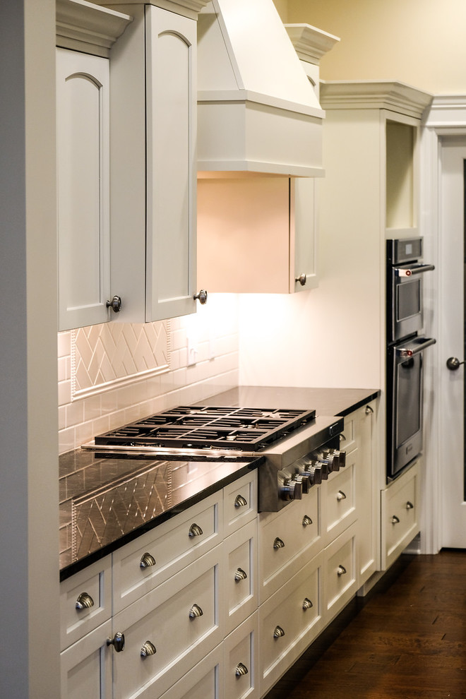 Eat-in kitchen - large transitional l-shaped dark wood floor and brown floor eat-in kitchen idea with an undermount sink, recessed-panel cabinets, white cabinets, granite countertops, white backsplash, stainless steel appliances, an island and blue countertops