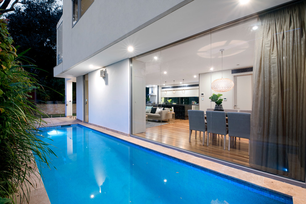 Inspiration for a mid-sized contemporary side yard rectangular lap pool in Sydney with natural stone pavers.