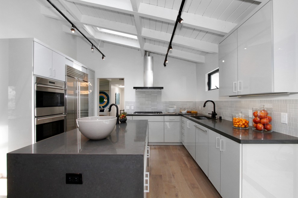 Mid-sized contemporary l-shaped eat-in kitchen in Los Angeles with flat-panel cabinets, grey cabinets, quartz benchtops, dark hardwood floors, multiple islands, an undermount sink, grey splashback, ceramic splashback and stainless steel appliances.