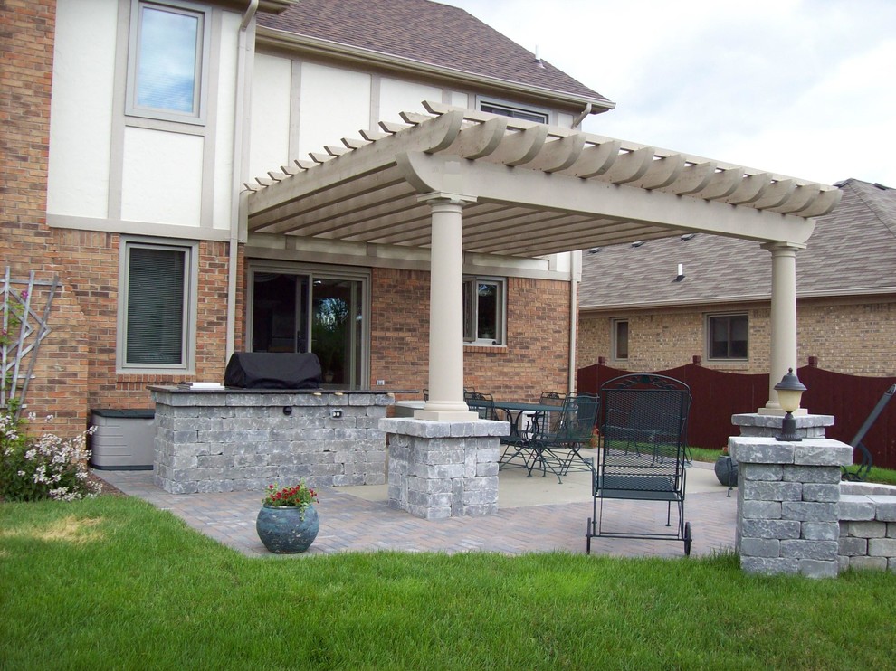 Photo of a backyard patio in Detroit with an outdoor kitchen, brick pavers and a pergola.