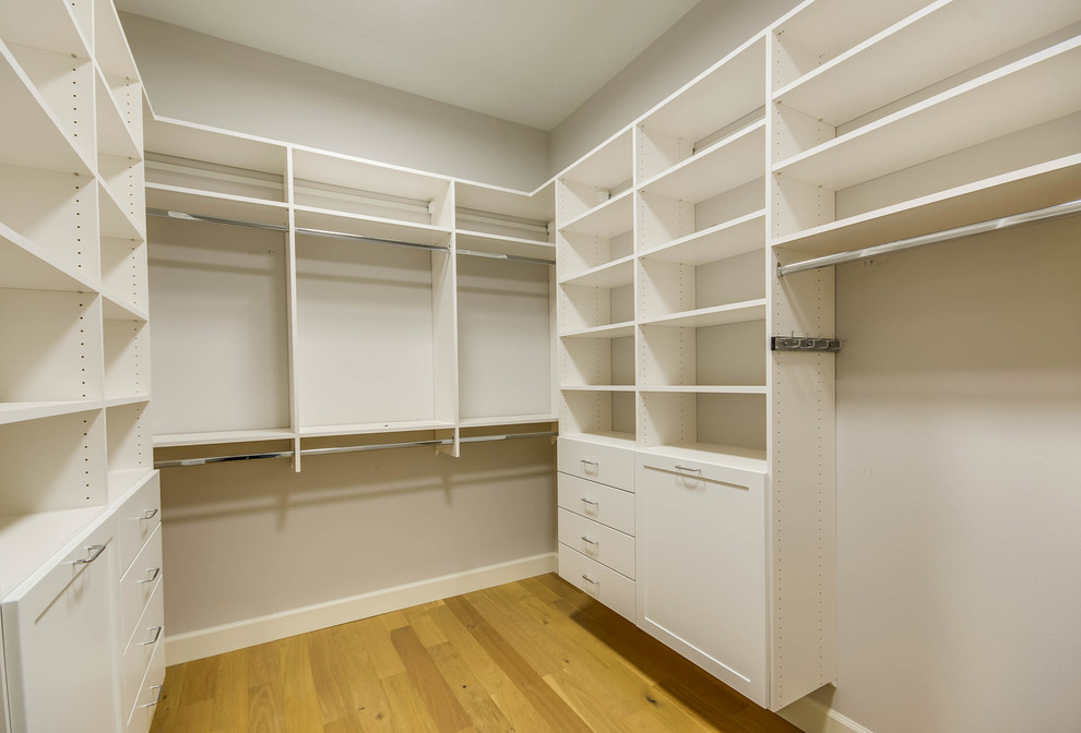 Inspiration for a large transitional gender-neutral walk-in wardrobe in Seattle with open cabinets, white cabinets and light hardwood floors.