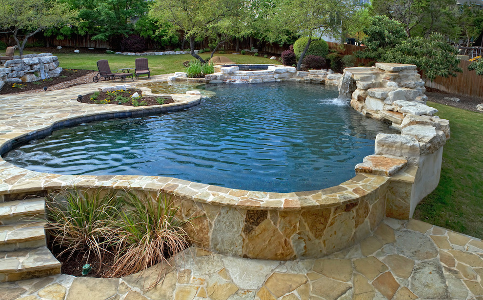 Photo of a mid-sized traditional backyard custom-shaped natural pool in Austin with natural stone pavers and a hot tub.