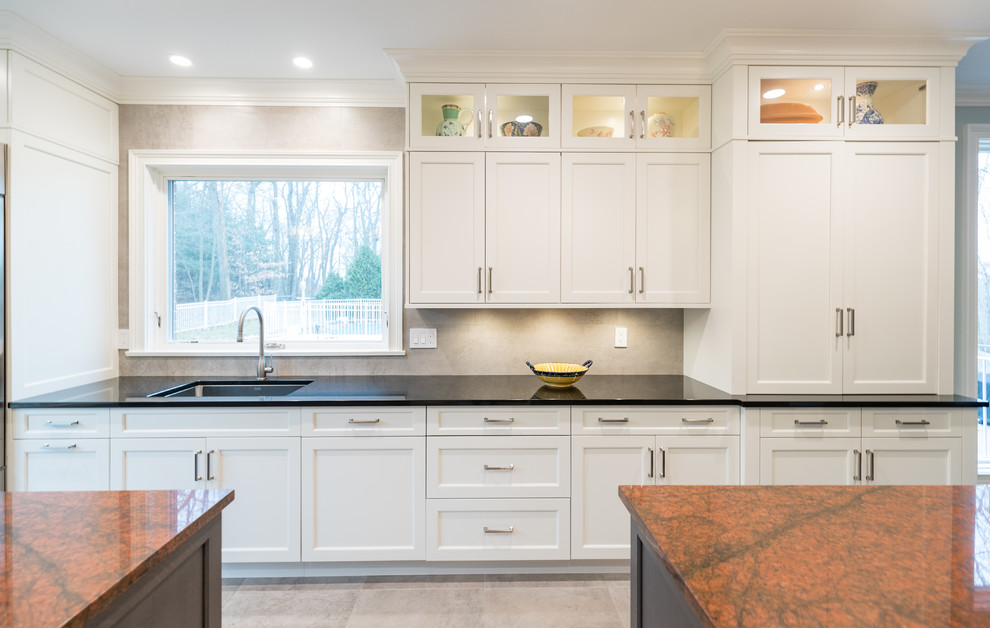 Large transitional galley ceramic tile and gray floor open concept kitchen photo in Bridgeport with an undermount sink, recessed-panel cabinets, white cabinets, granite countertops, gray backsplash, ceramic backsplash, stainless steel appliances, two islands and black countertops