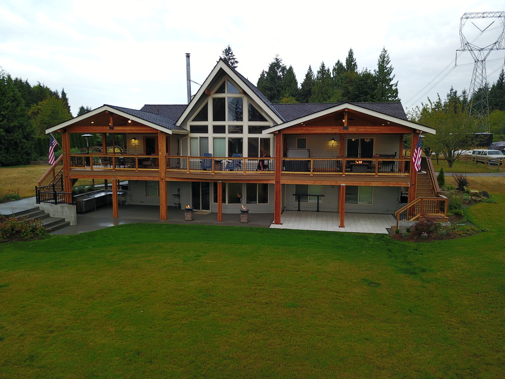 Large mountain style backyard outdoor kitchen deck photo in Seattle with a roof extension