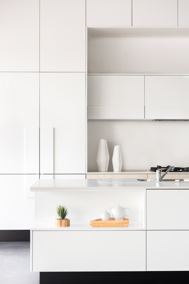 Inspiration for a medium sized contemporary galley kitchen in Perth with white cabinets, engineered stone countertops, white splashback, concrete flooring, an island and white worktops.