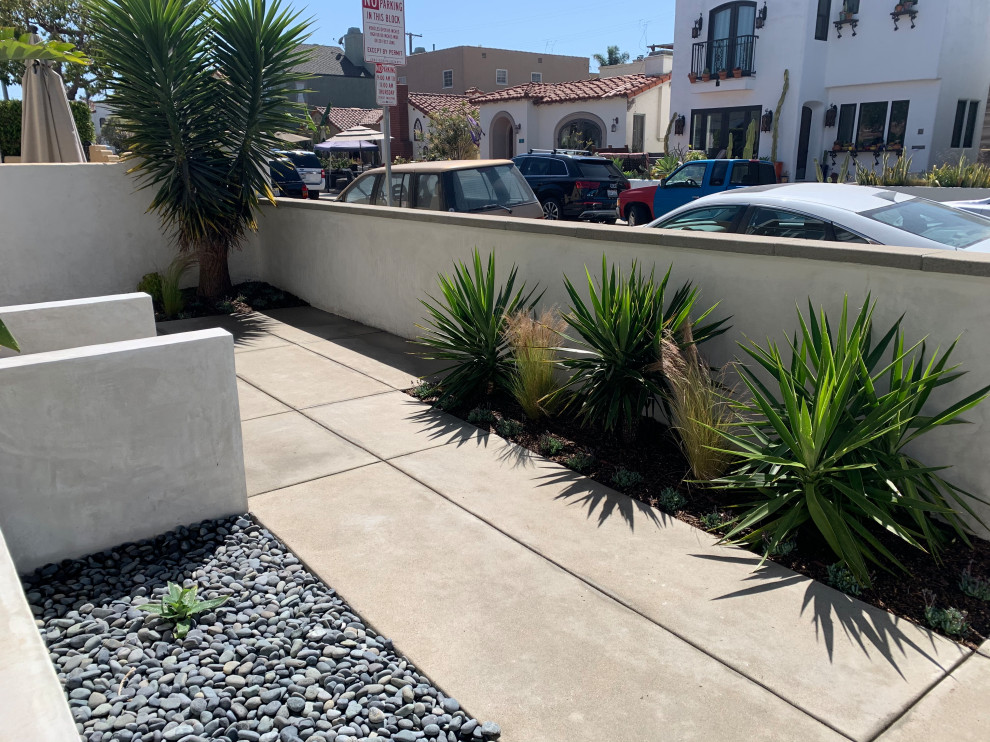 Small modern front yard full sun garden in Los Angeles with with privacy feature, river rock and a wood fence.