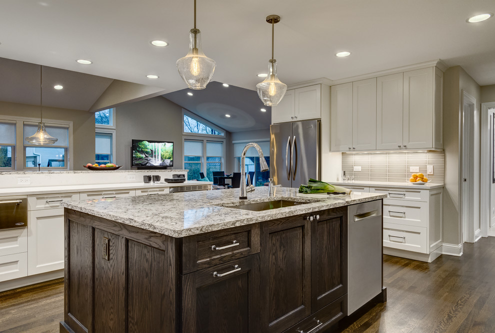 This is an example of a transitional u-shaped eat-in kitchen in Chicago with an undermount sink, shaker cabinets, white cabinets, grey splashback, stainless steel appliances, dark hardwood floors and with island.
