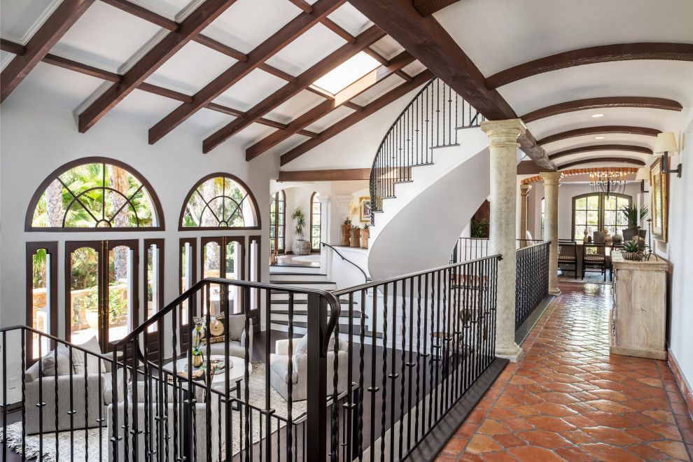 Mid-sized mediterranean hallway in Orange County with white walls, terra-cotta floors and exposed beam.
