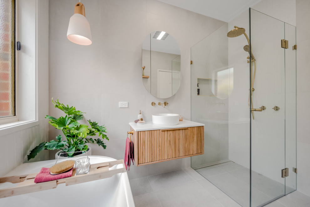 Inspiration for a contemporary bathroom in Melbourne with flat-panel cabinets, light wood cabinets, a built-in shower, grey tiles, a vessel sink, grey floors, a hinged door, white worktops, a single sink and a floating vanity unit.