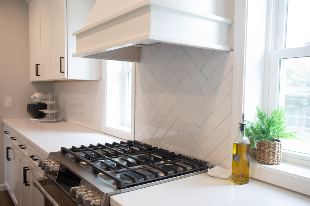 Transitional vinyl floor kitchen photo with shaker cabinets, white cabinets, quartz countertops, white backsplash, porcelain backsplash, stainless steel appliances and white countertops