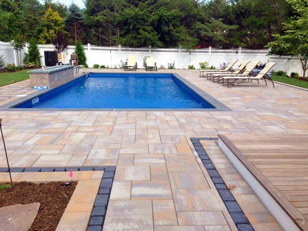 Mid-sized transitional backyard pool in New York with natural stone pavers.