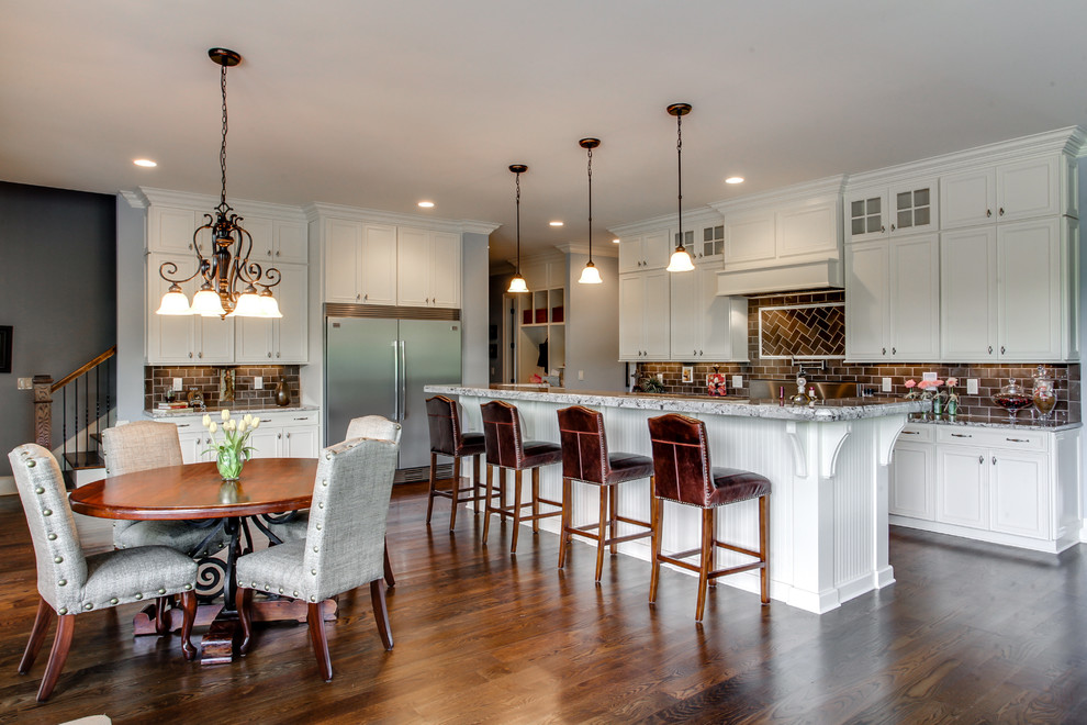 This is an example of a traditional l-shaped eat-in kitchen in Nashville with recessed-panel cabinets, white cabinets, brown splashback, subway tile splashback and stainless steel appliances.